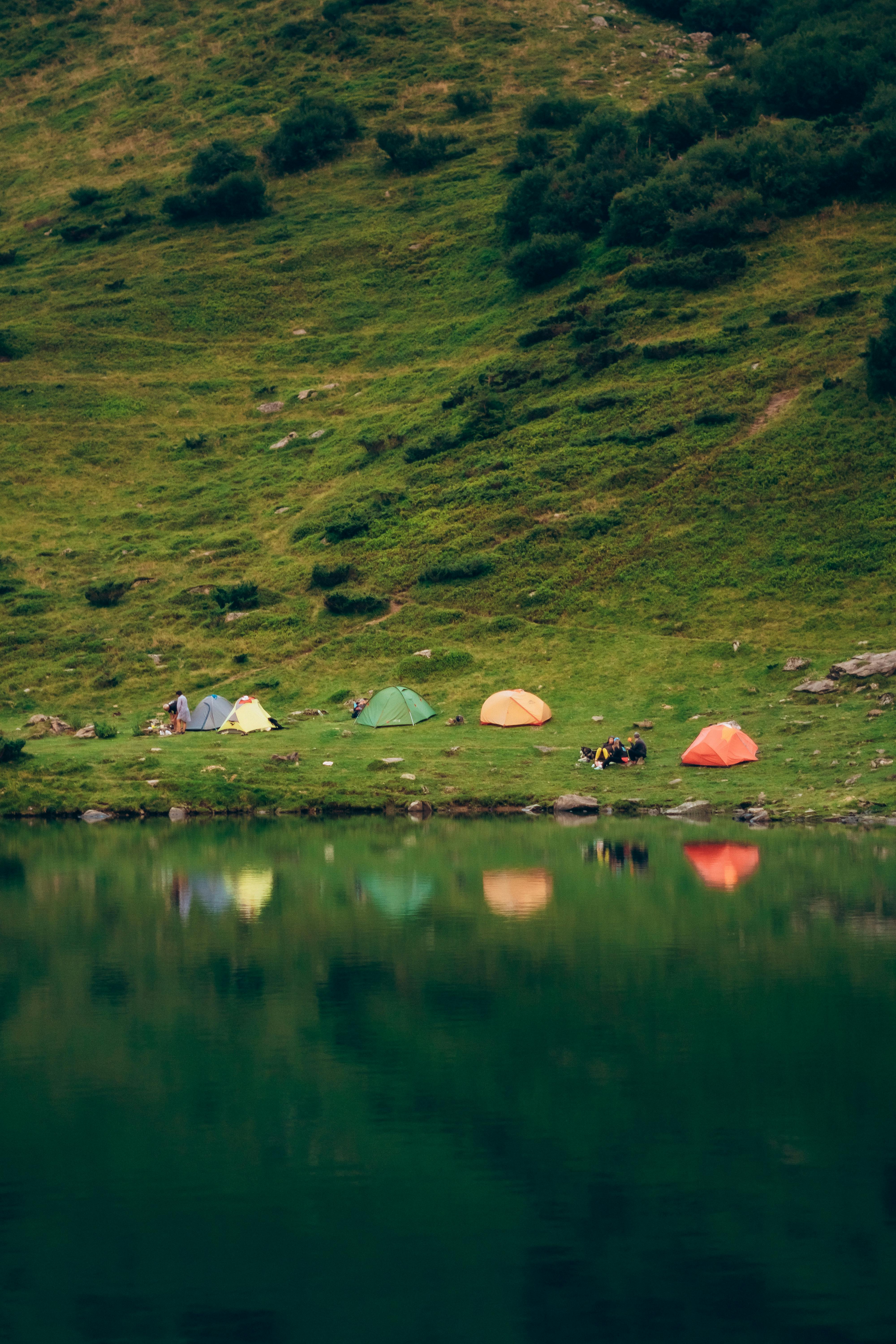 Randonneurs en bivouac au bord d'un lac de montagne dans les Pyrénées, tentes installées dans un paysage brumeux et minéral