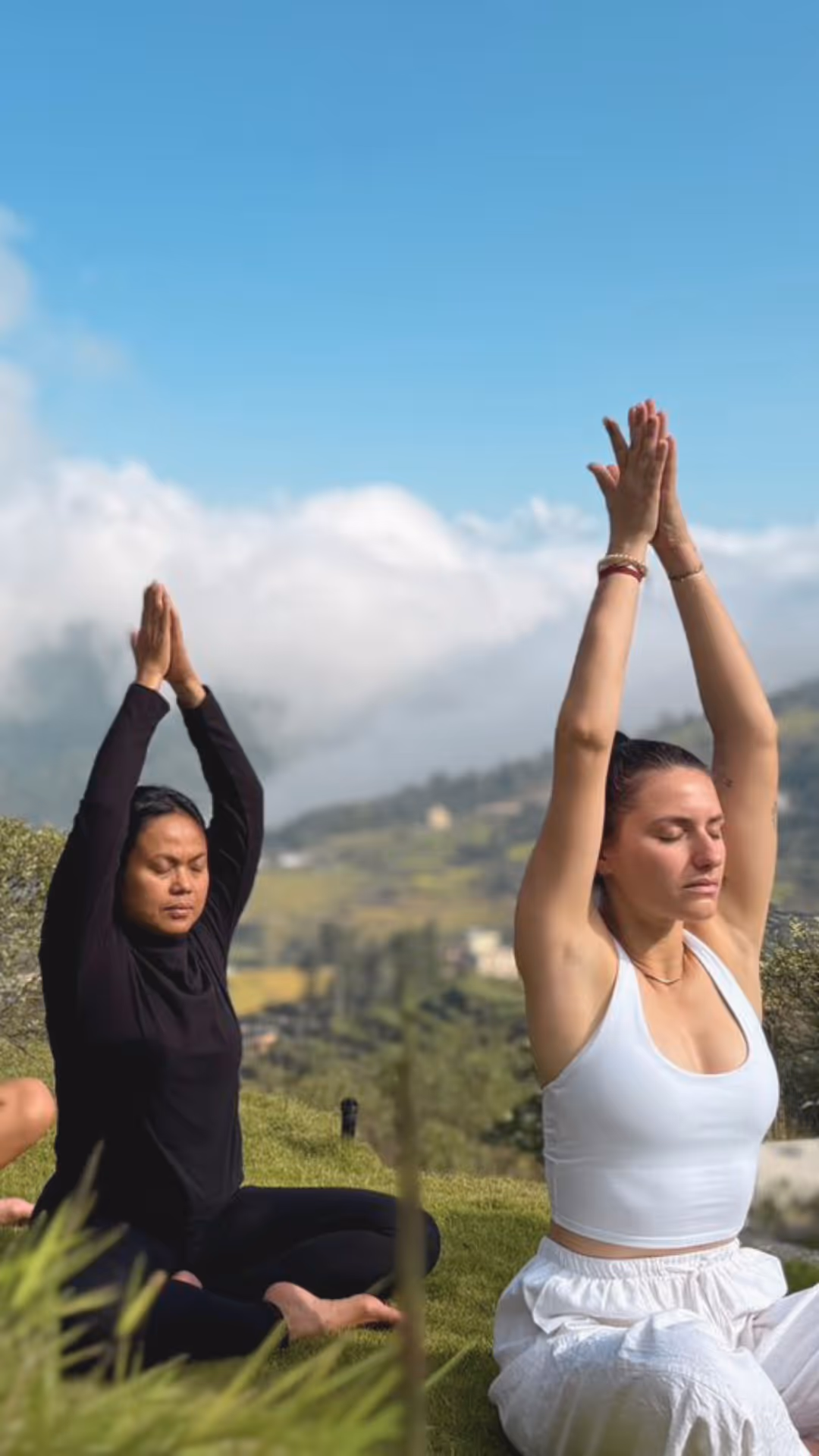 Groupe en séance de yoga en plein air face aux montagnes du Népal, mains jointes levées vers le ciel