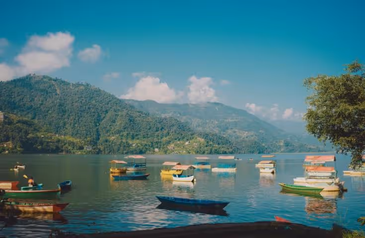Paysage paisible de Pokhara avec bateaux et montagnes au loin