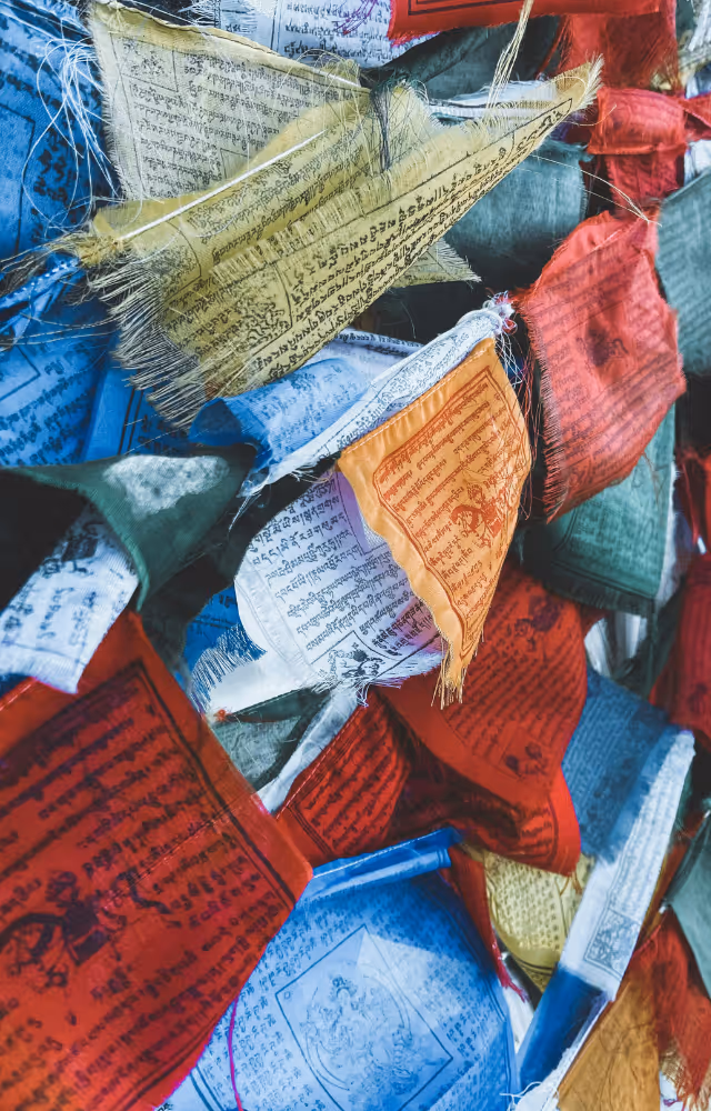 Drapeaux de prières tibétains colorés accrochés en extérieur.