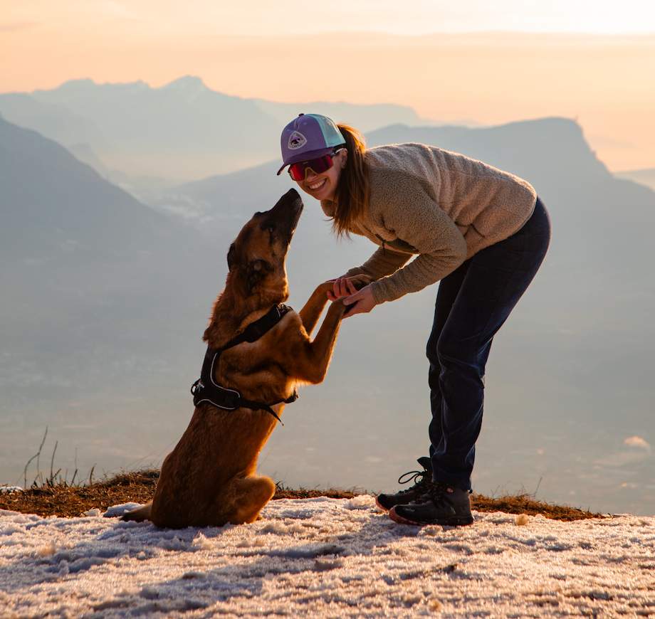 Randonneuse et son chien face au coucher de soleil en montagne — week-end La Meute en Savoie.