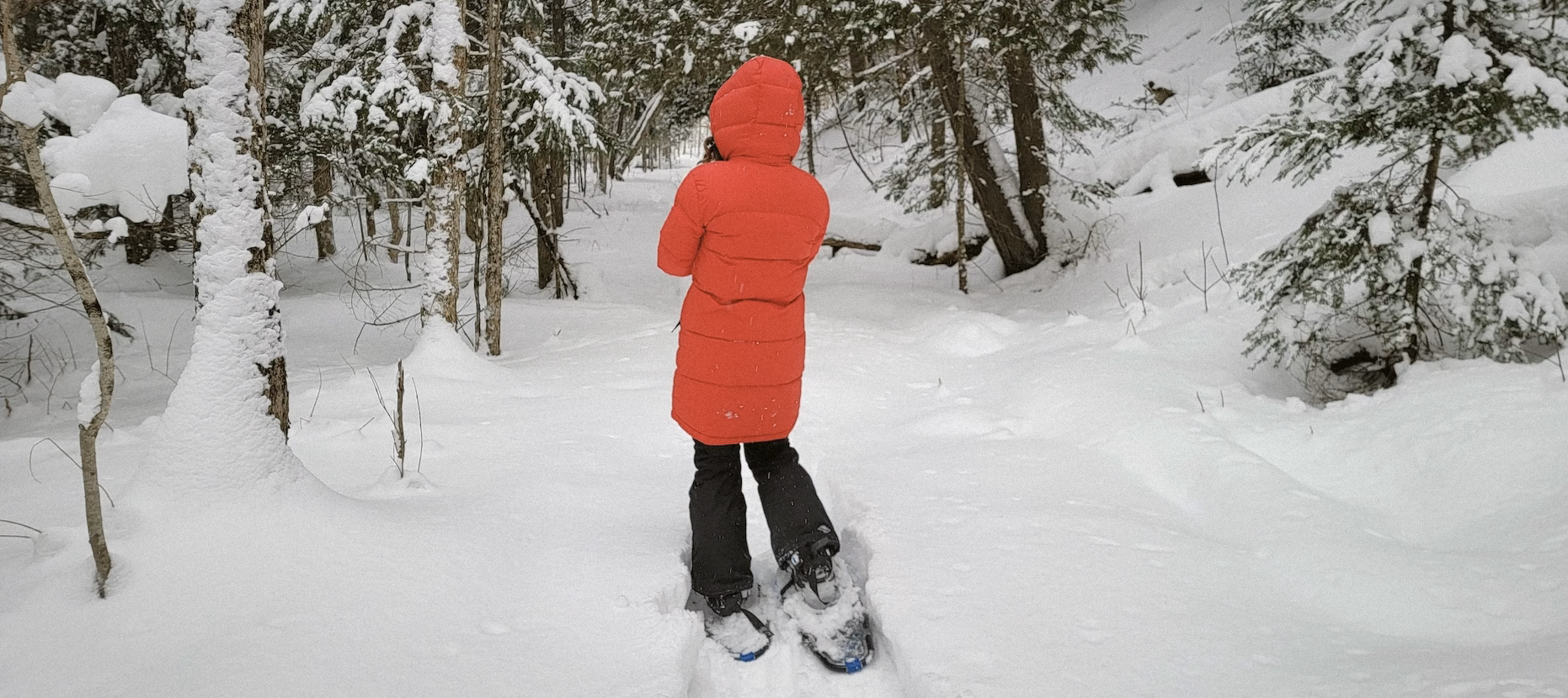 Randonneuse en doudoune rouge en raquettes dans la neige, séjour Raquettes flow.