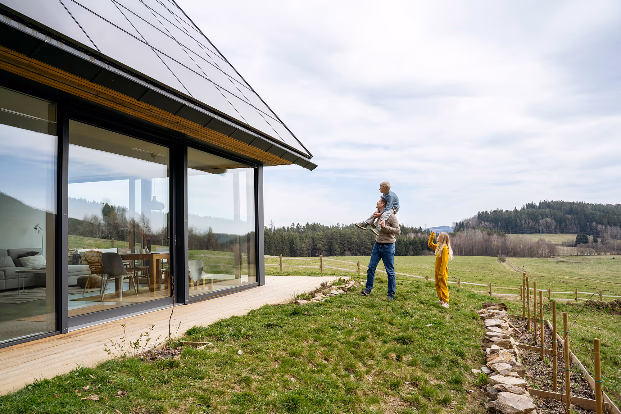 Father arrives home with his kids. The house has floor-to-ceiling windows and solar panels.