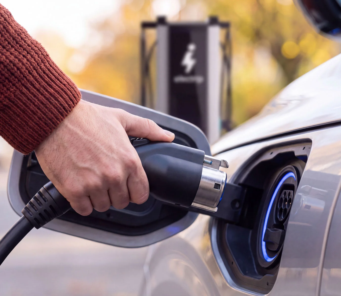 Mano che inserisce il connettore nella presa di ricarica dell'auto elettrica