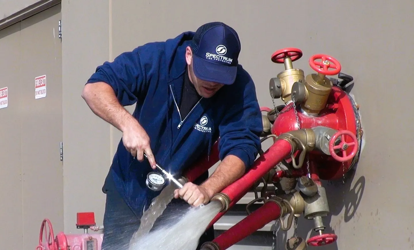 Rows of red fire extinguishers with labels in a storage area and a person handling one extinguisher in the background.