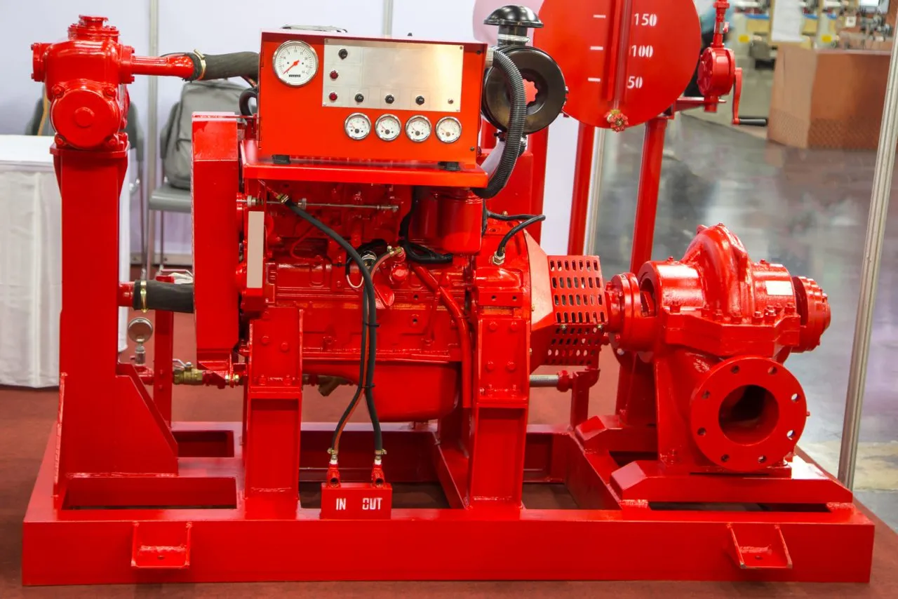 Large red industrial fire pump system with gauges and pipes on a base platform.