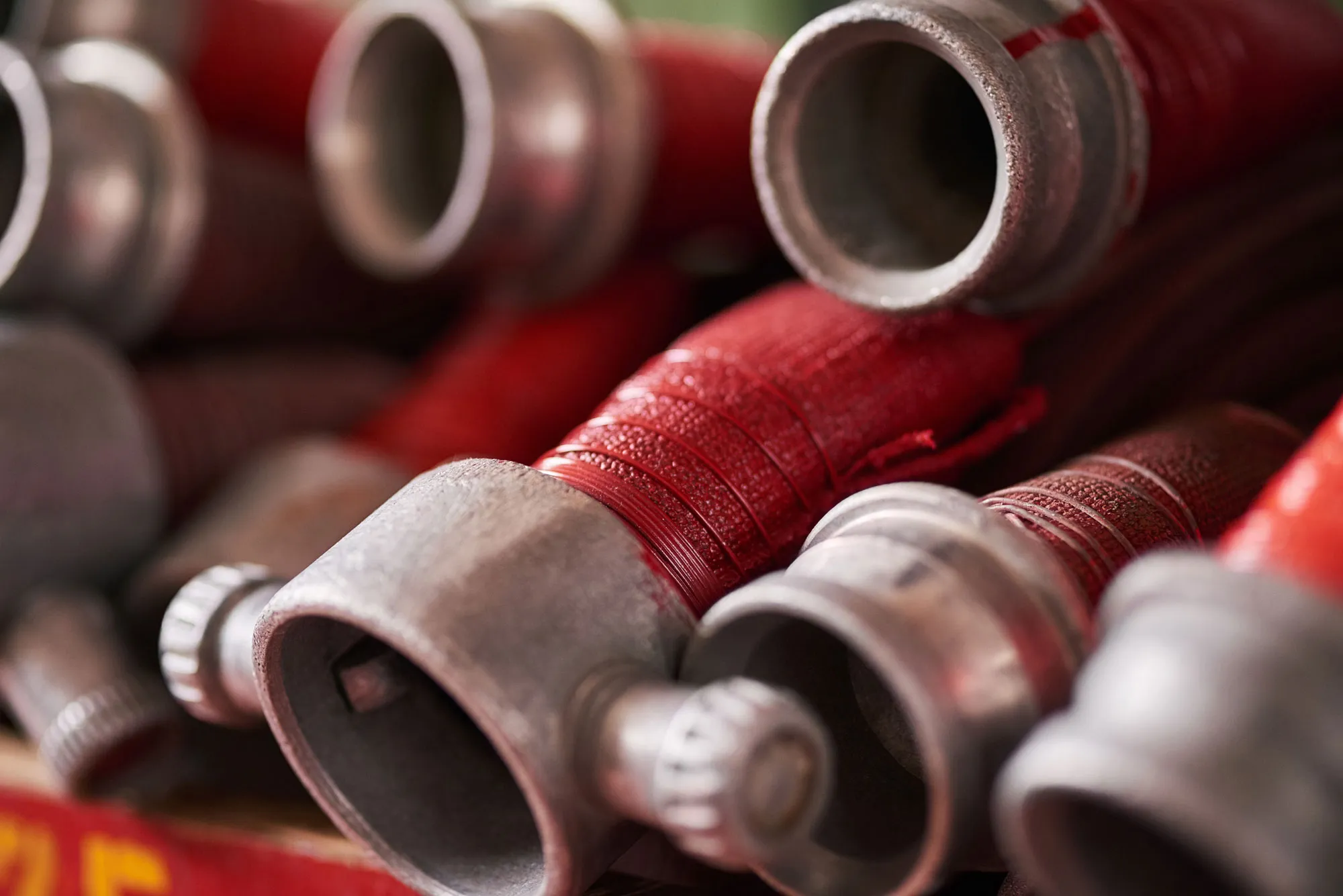 Close-up of red fire hoses with metal couplings stacked together.