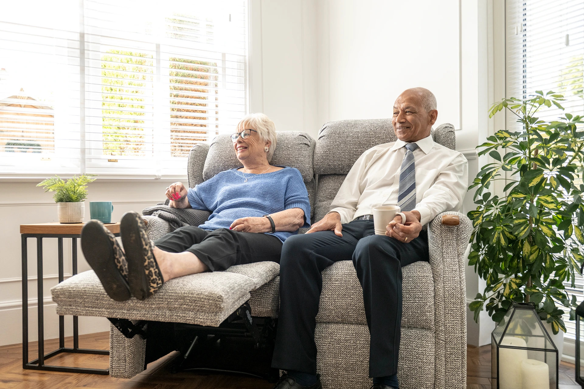 man and woman sat on 2 seater riser recliner sofa
