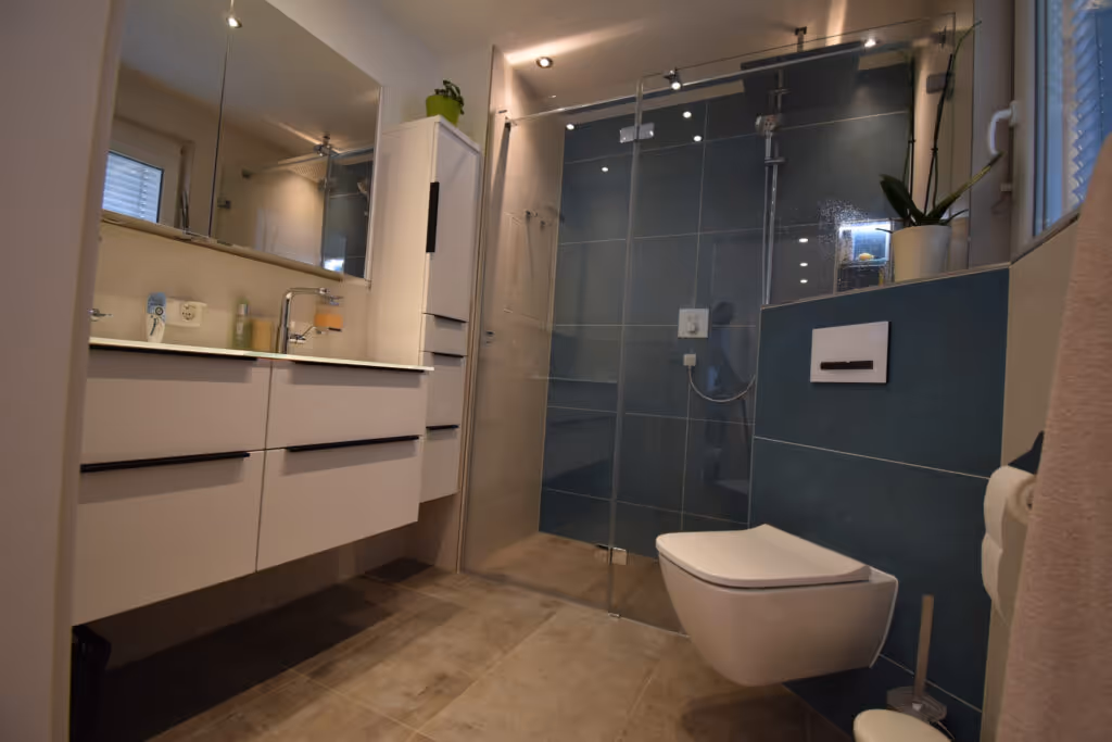 Modernes renoviertes Bad mit weißen Waschbecken grauen fliesen und großer Stehdusche mit blauen fliesen an der Wand