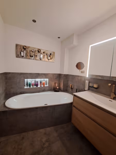Stilvolles Bad mit braunen Wandfliesen, Holzunterschrank und eingelassener Badewanne.