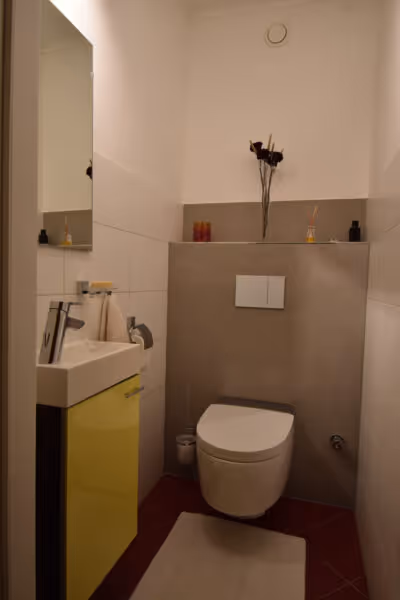 Kleines WC mit gelben Wandfliesen und schmalem Waschbecken vor Renovierung.