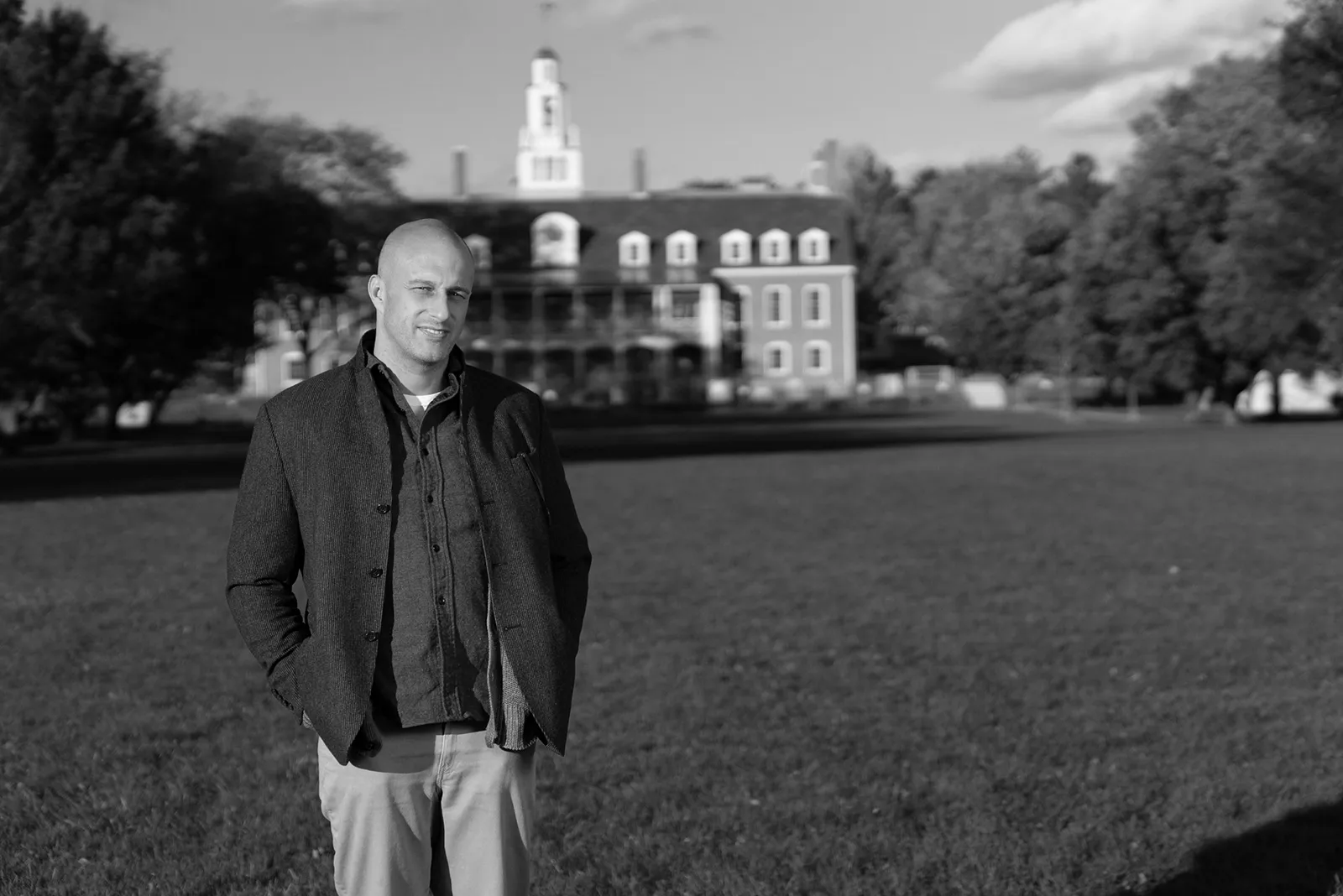 photo of man standing in a field in front of a school
