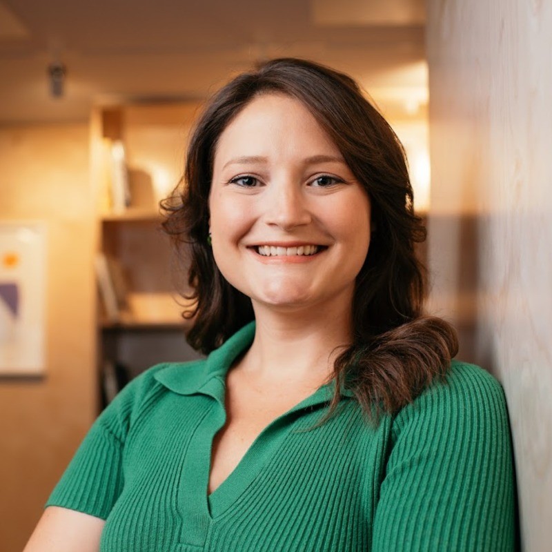A portrait of Catherine Boudreau, A Brunette Woman Leaning Against a Wall With an Inviting Smile 