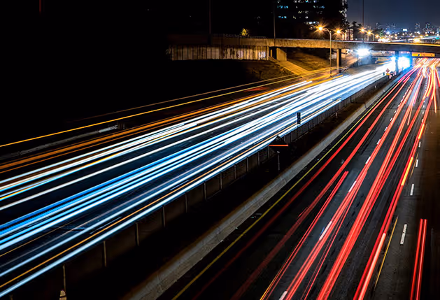 Langzeitbelichtung einer Autobahn auf der die Scheinwerfer der Autos als Streifen sichtbar sind.