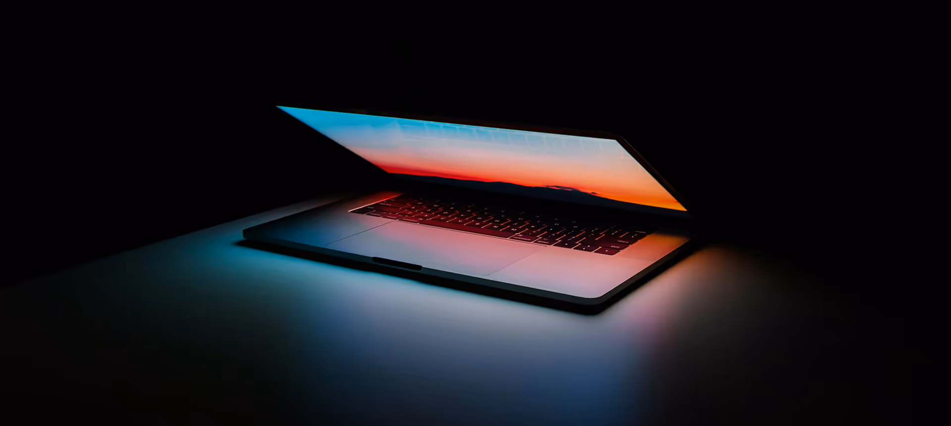 Ein fast zugeklapptes Macbook in einem dunklen Raum