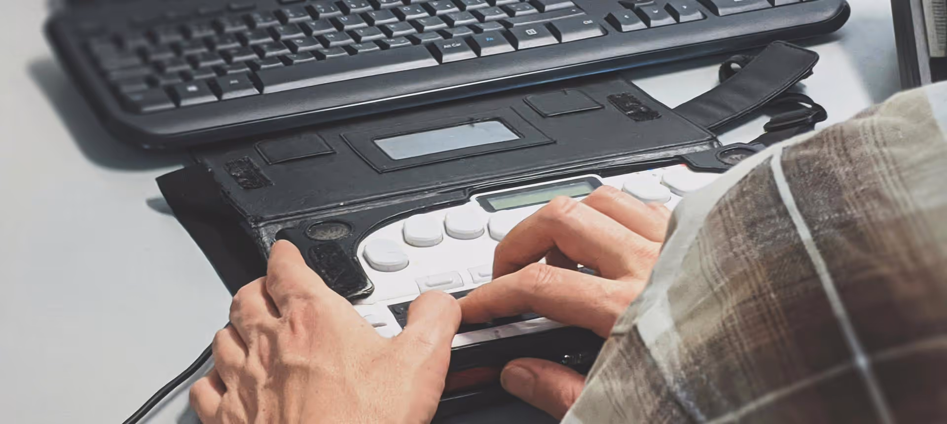 Person, die unterstützende Technologien und Braillezeilen mit einer taktilen Tastatur verwendet.