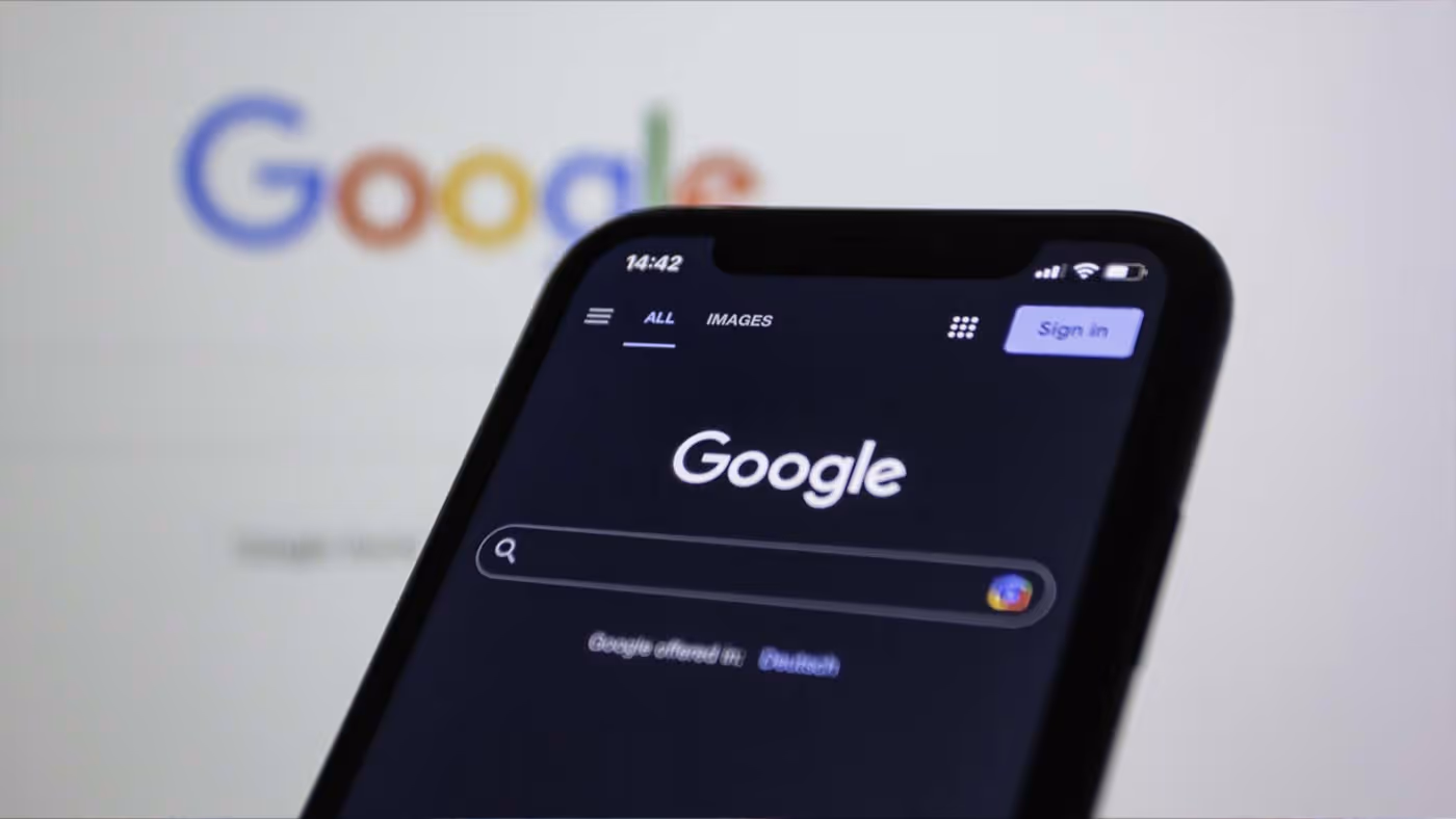 Ein Smartphone mit der Google Suche geöffnet, im Hintergrund unscharf das Google-Logo.