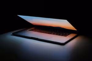 Ein fast zugeklapptes Macbook in einem dunklen Raum