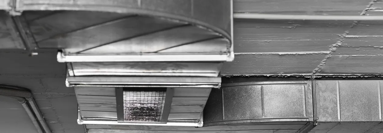 Black and white close-up of industrial ventilation duct with metal grid