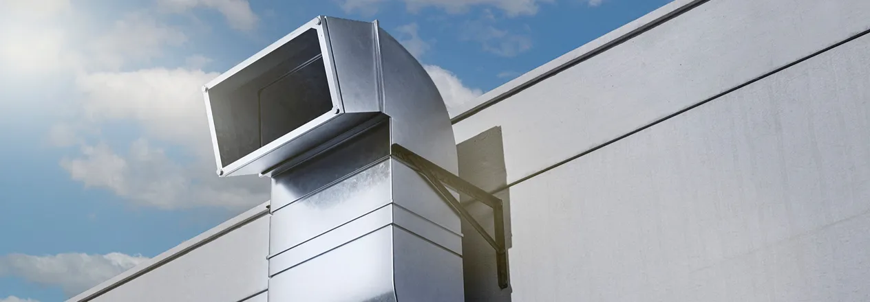 Large metallic industrial ventilation duct on modern building exterior