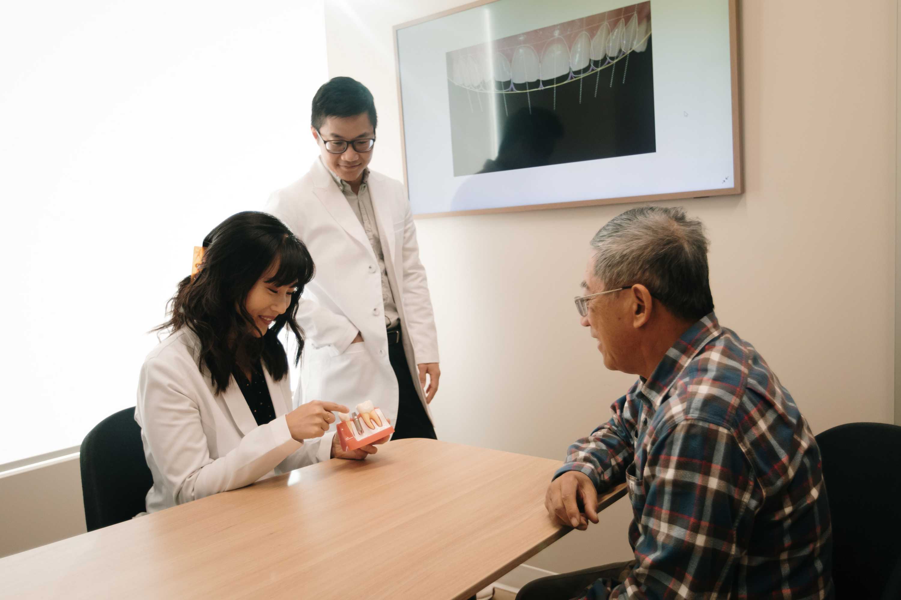 Dr. Linda Lee showing a patient a model of teeth while sitting at a table