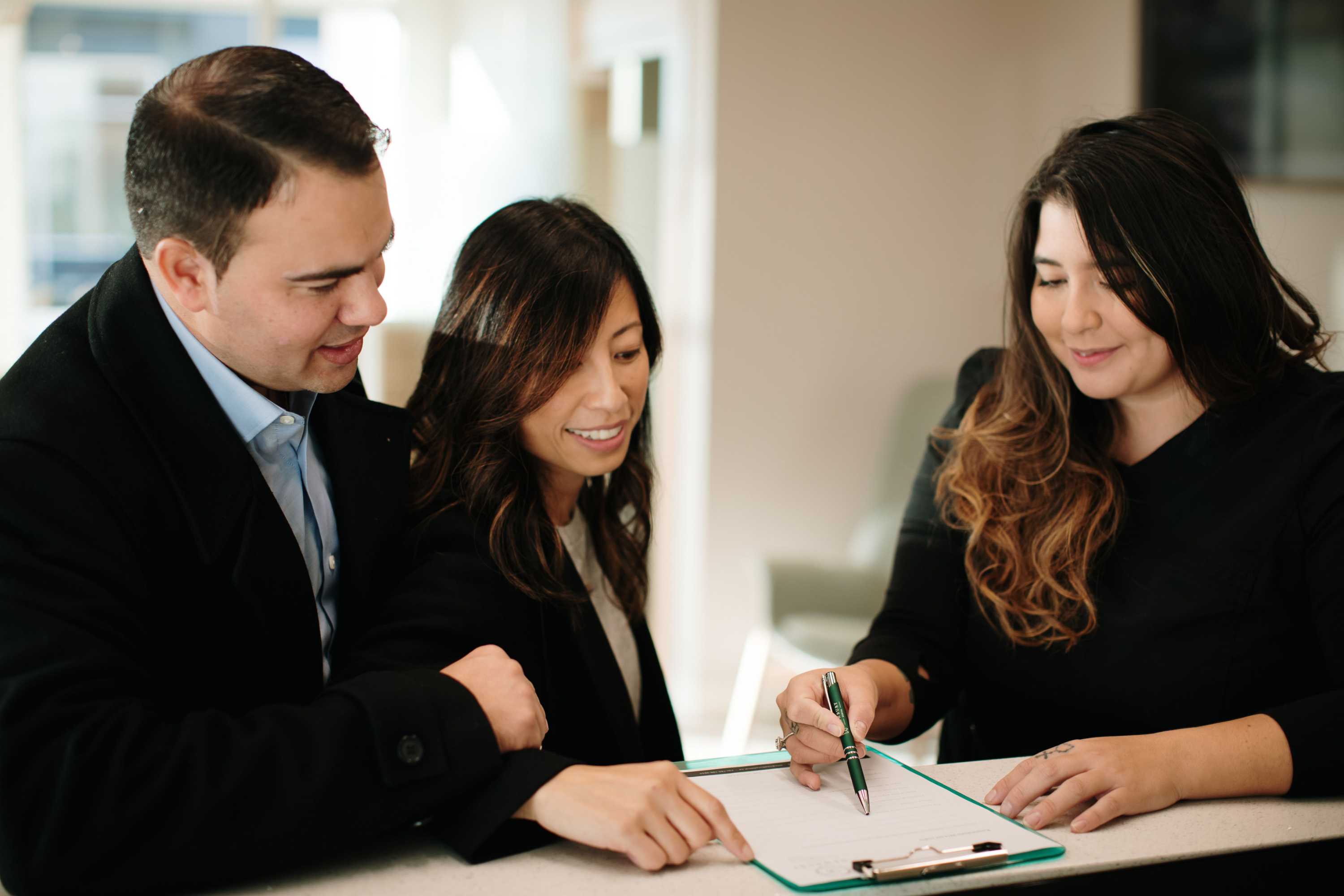 Office manager instructing a couple on how to fill out a "New Patient" form in Newbury Dental