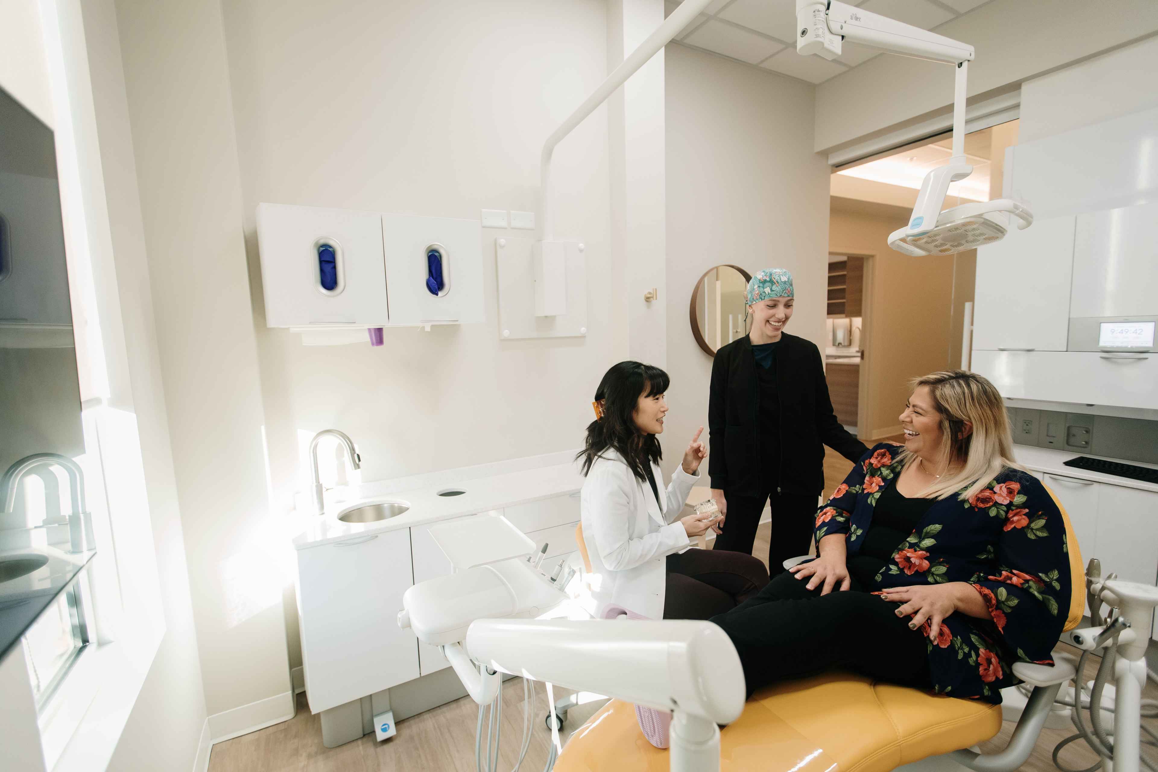 Dr. Lee and a dental assistant talking and laughing with a patient in an operatory