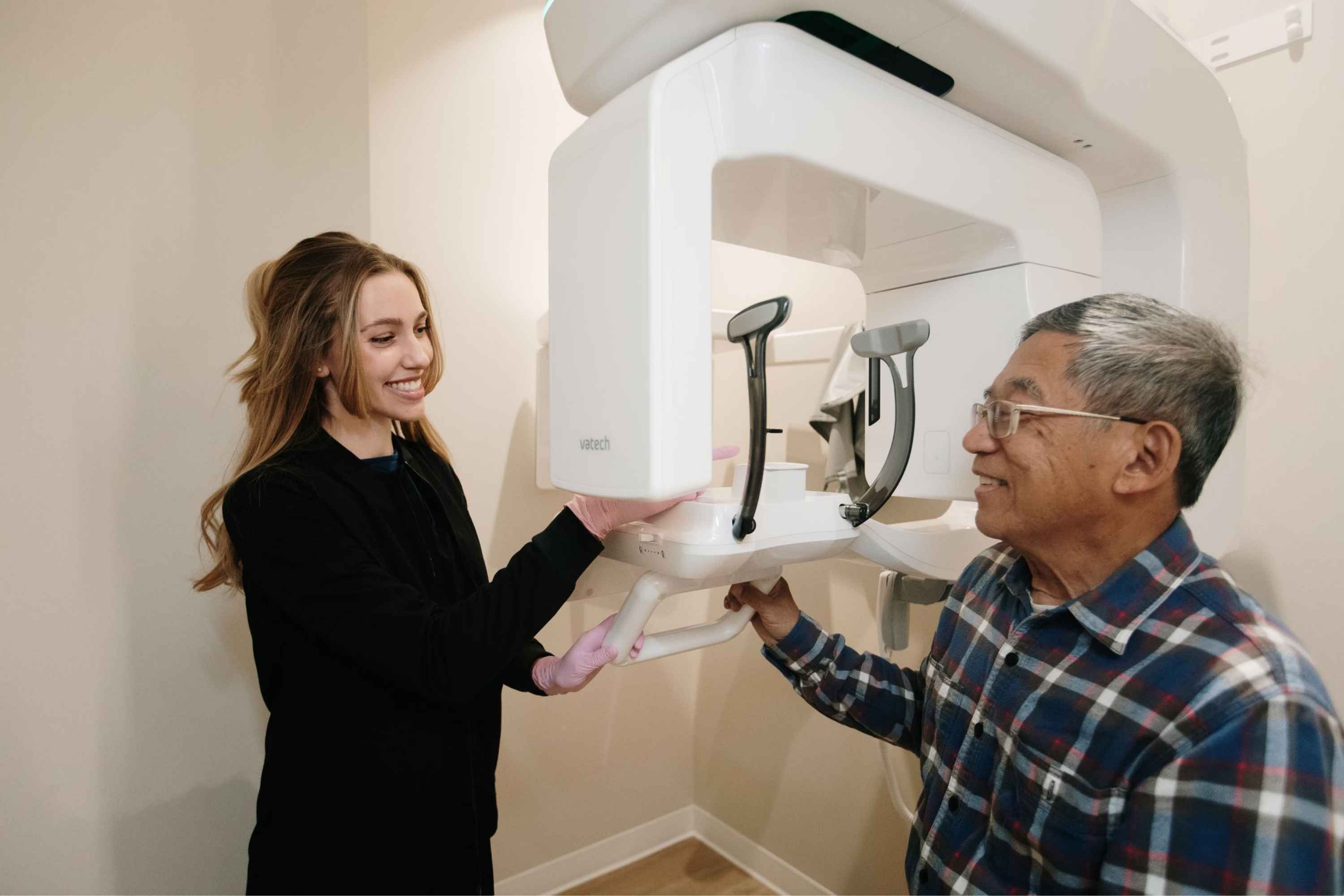 Hygienist aiding an elderly patient to their panoramic dental x-ray