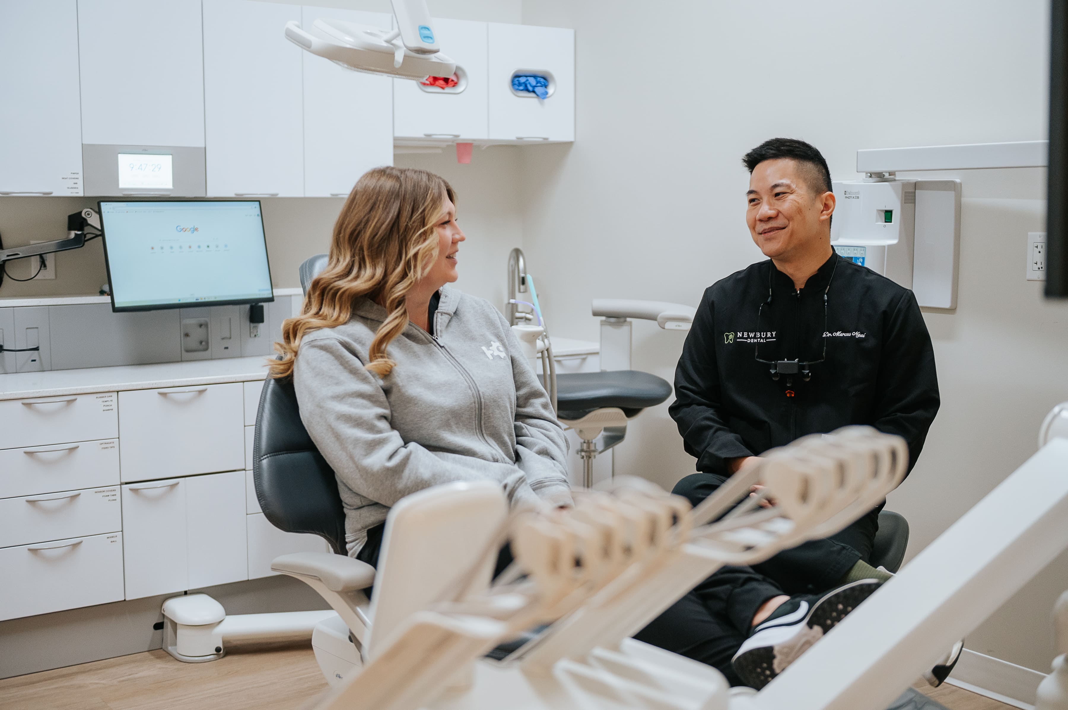 Dr. Lee and a dental assistant talking and laughing with a patient in an operatory