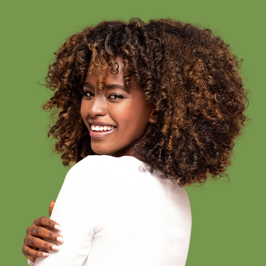 A person with curly hair smilingDescription automatically generated