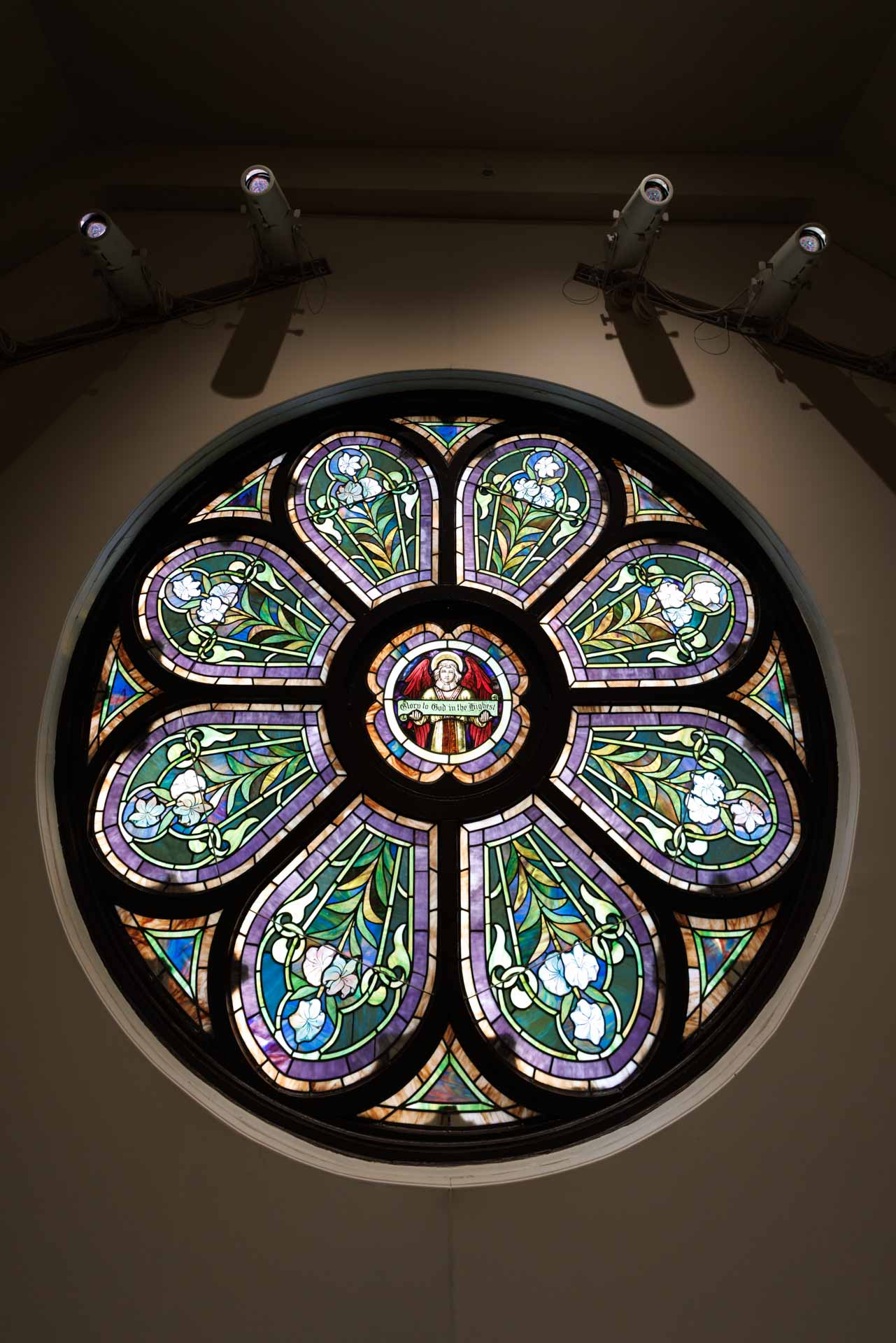 Stained glass rose window illuminated in the chapel, reflecting donor-supported worship and formation at Trinity