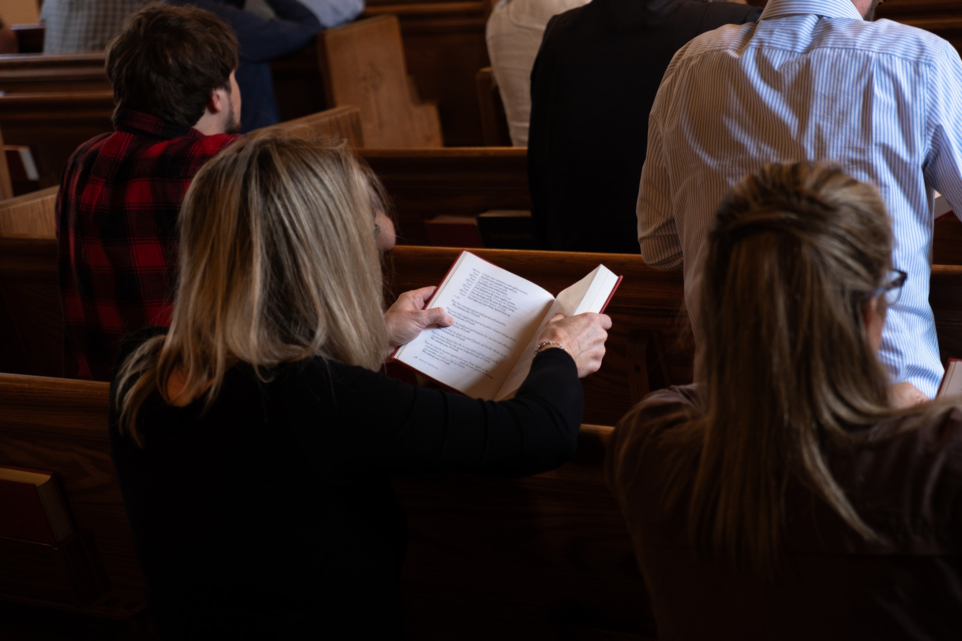 Stained glass depicting a kneeling woman in blue and red robes facing an angel in white with wings, holding a lily, framed by vibrant colors.