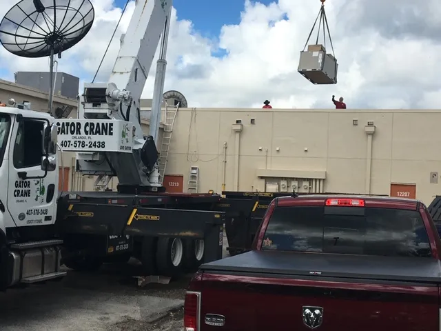 Gator Crane lifting heavy box with satellite dish in background