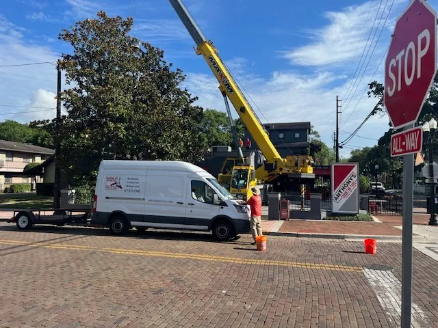 Yellow crane and white van at urban intersection with stop sign