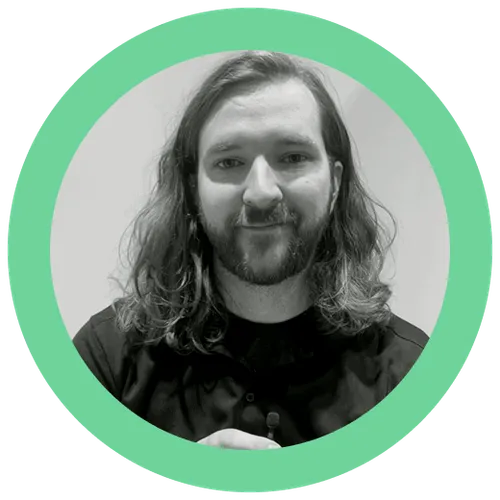 Black-and-white portrait of a smiling man with long hair and a beard, wearing a dark shirt.