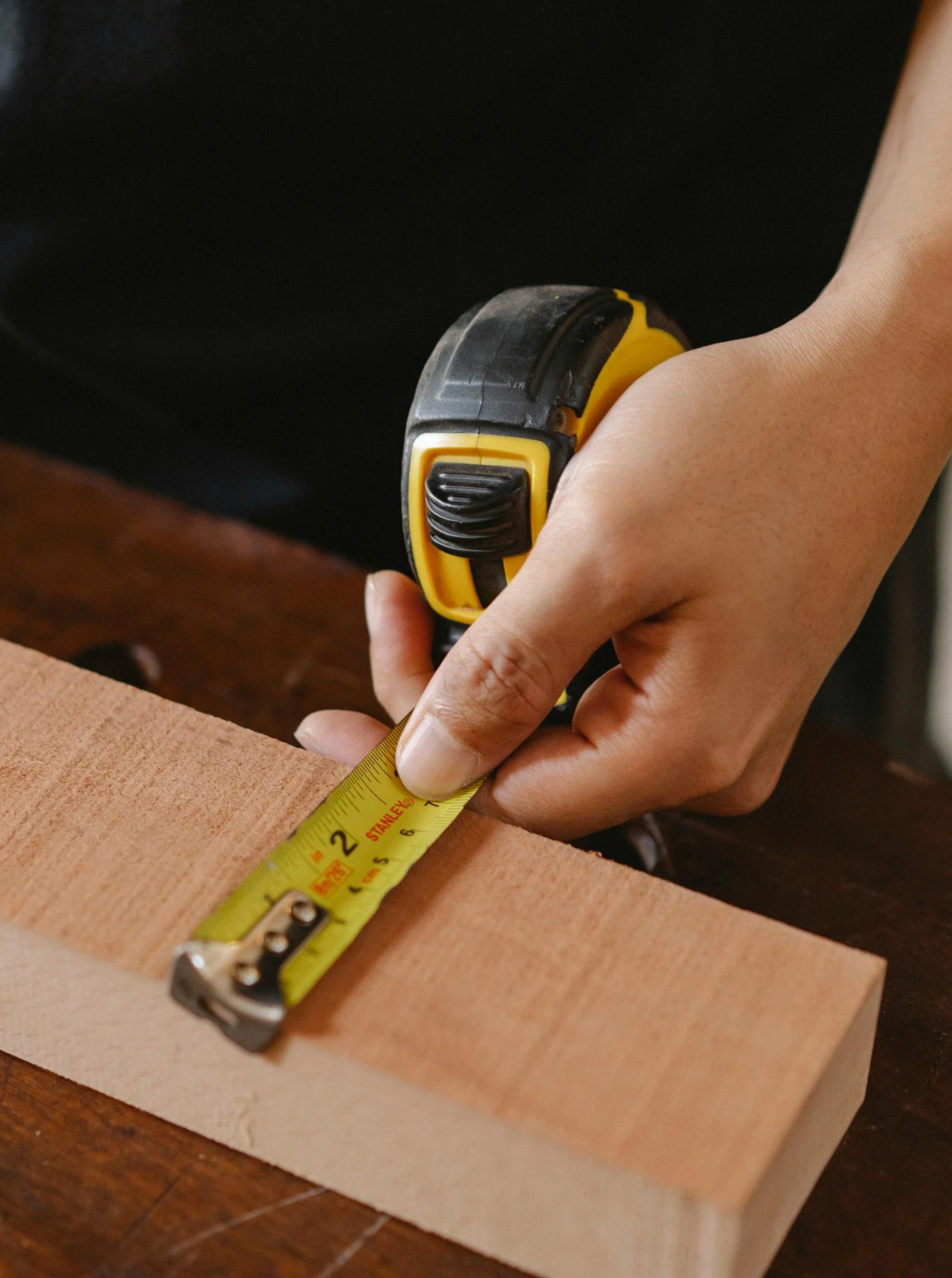 Person measuring wood block representing penis size, exploring if TRT increases penile growth