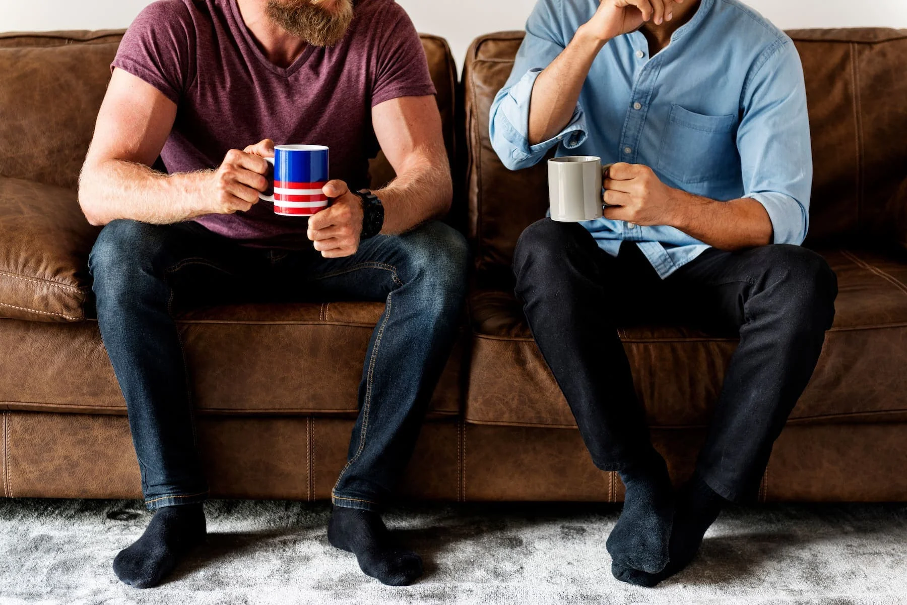 Two guys sitting on the sofa talking to each other