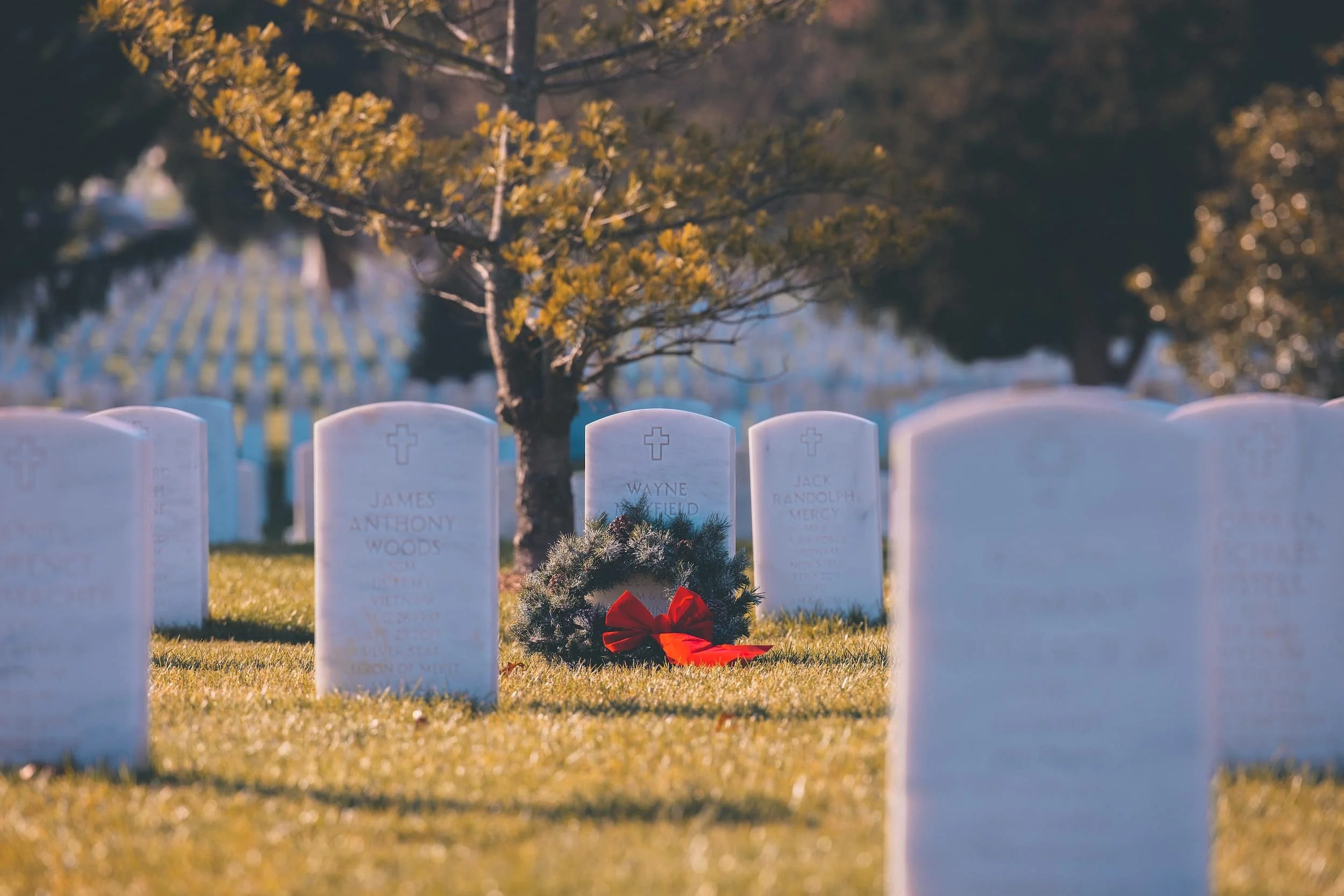 Tombstone in a cemetery with a wreath at the base