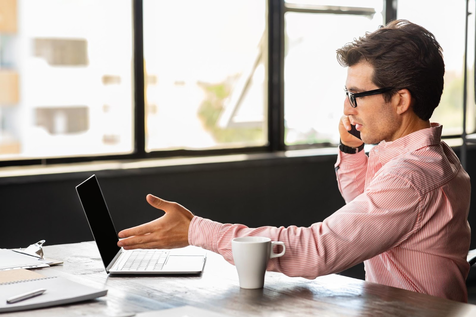 man talking on a phone while using a laptop