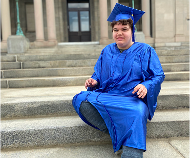 Portrait of smiling neurodivergent teenage boy wearing a graduation gown