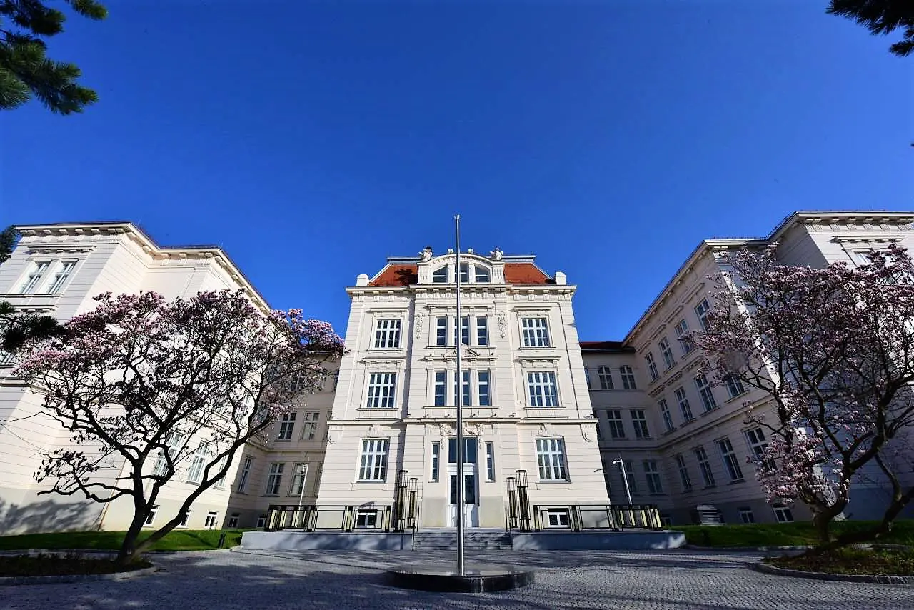 Celkový pohľad na historickú bielu budovu ambasády pod modrou oblohou, s radmi bielych rustikálnych okien.