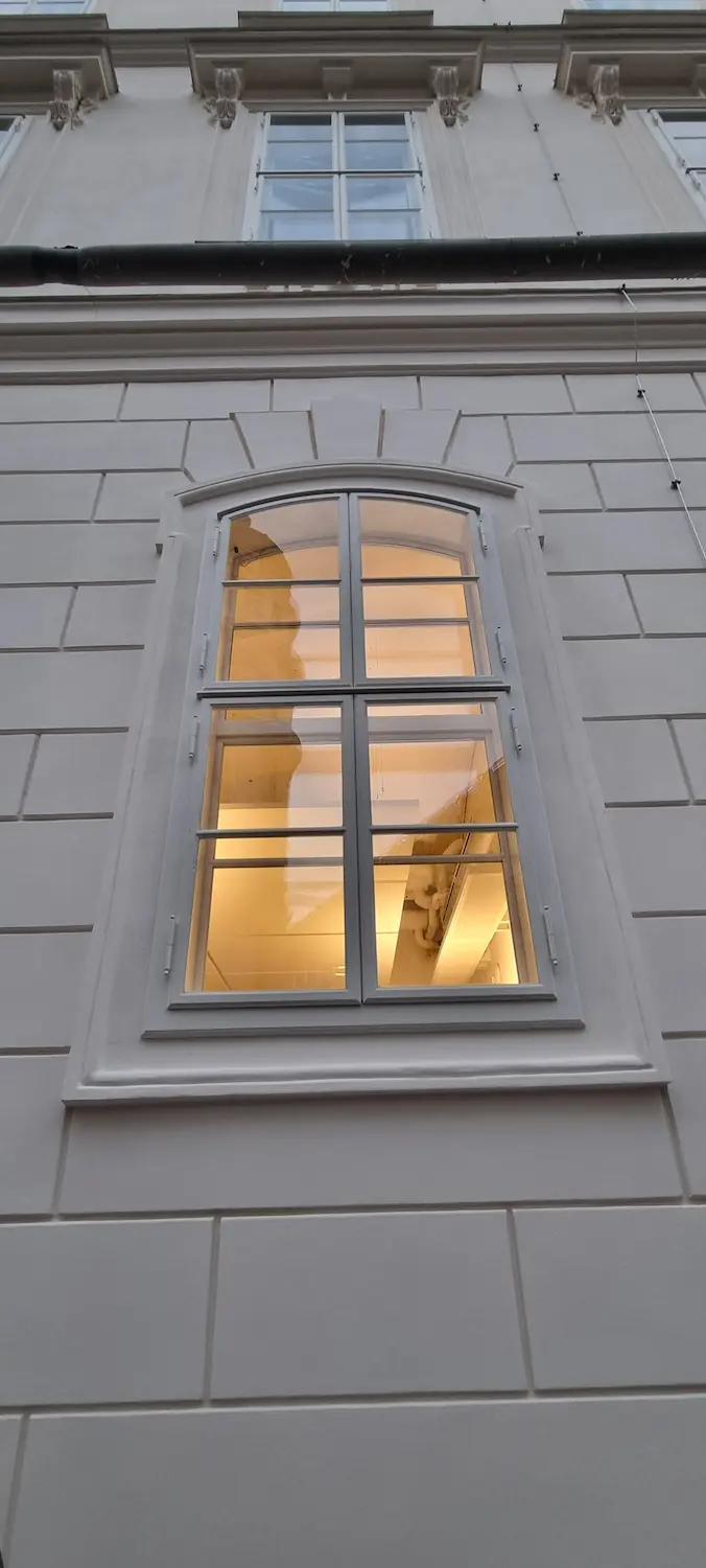 Nočný pohľad na presvetlené drevené kastlové okno so štíhlymi rámami.