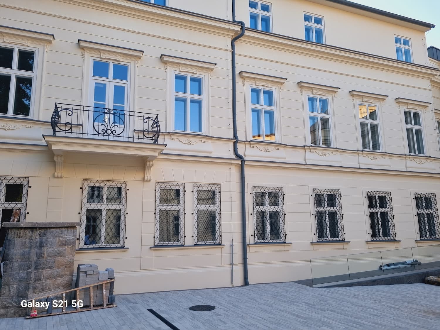 Záber na fasádu nádvoria s balkónom s kovaným zábradlím a mrežami na kastlových oknách prízemia.