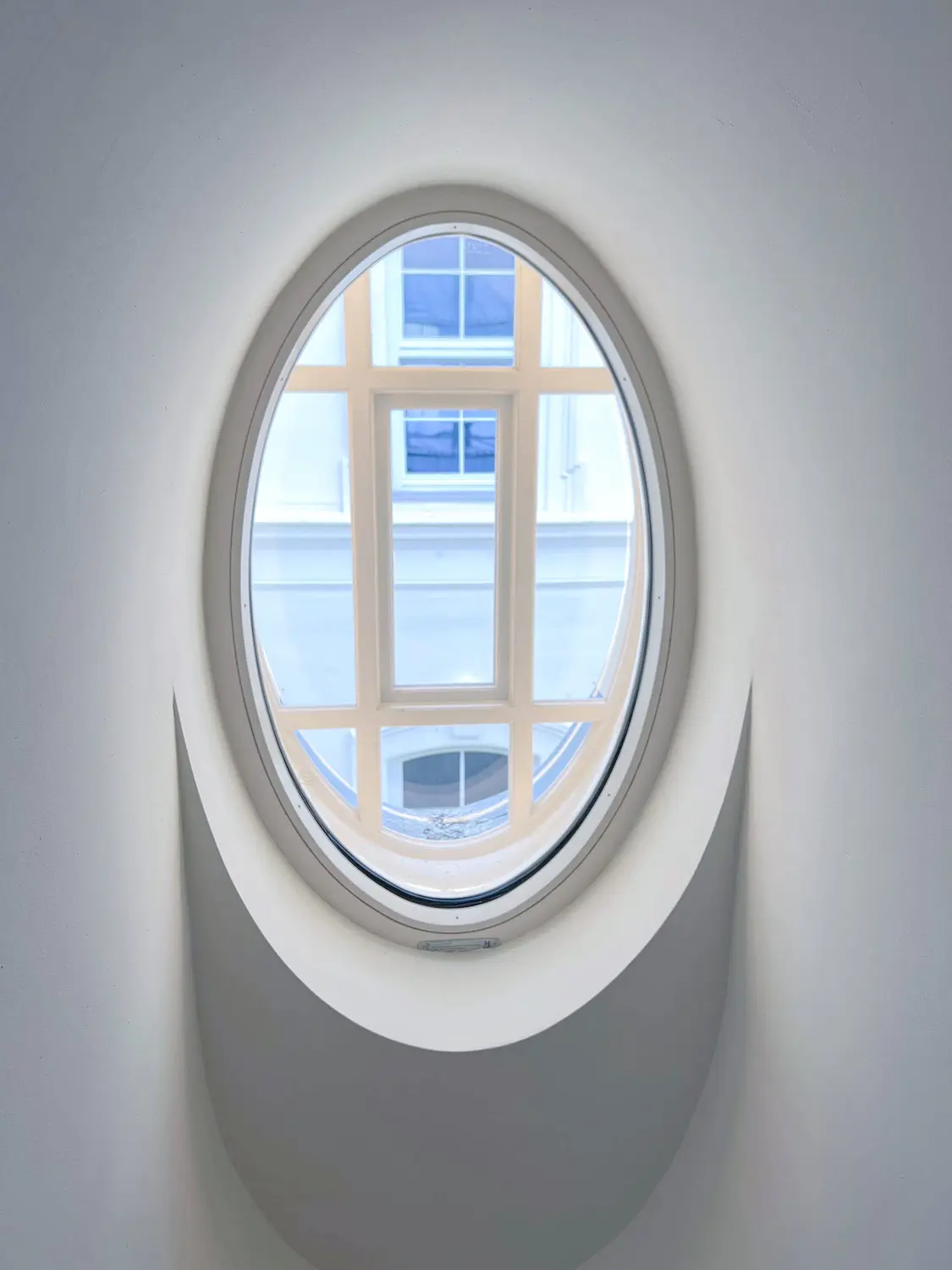 Moderné oválne drevené kastlové okno osadené v čistom bielom ostení.