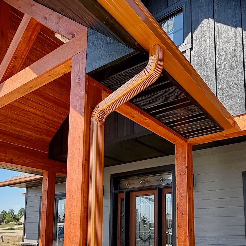 copper color seamless box gutter with a round corrugated downspout