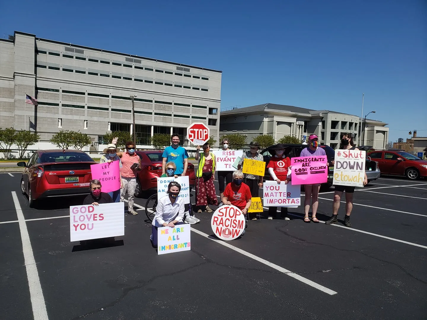 Group of activists holding protest signs in front of Etowah County Detention Center.