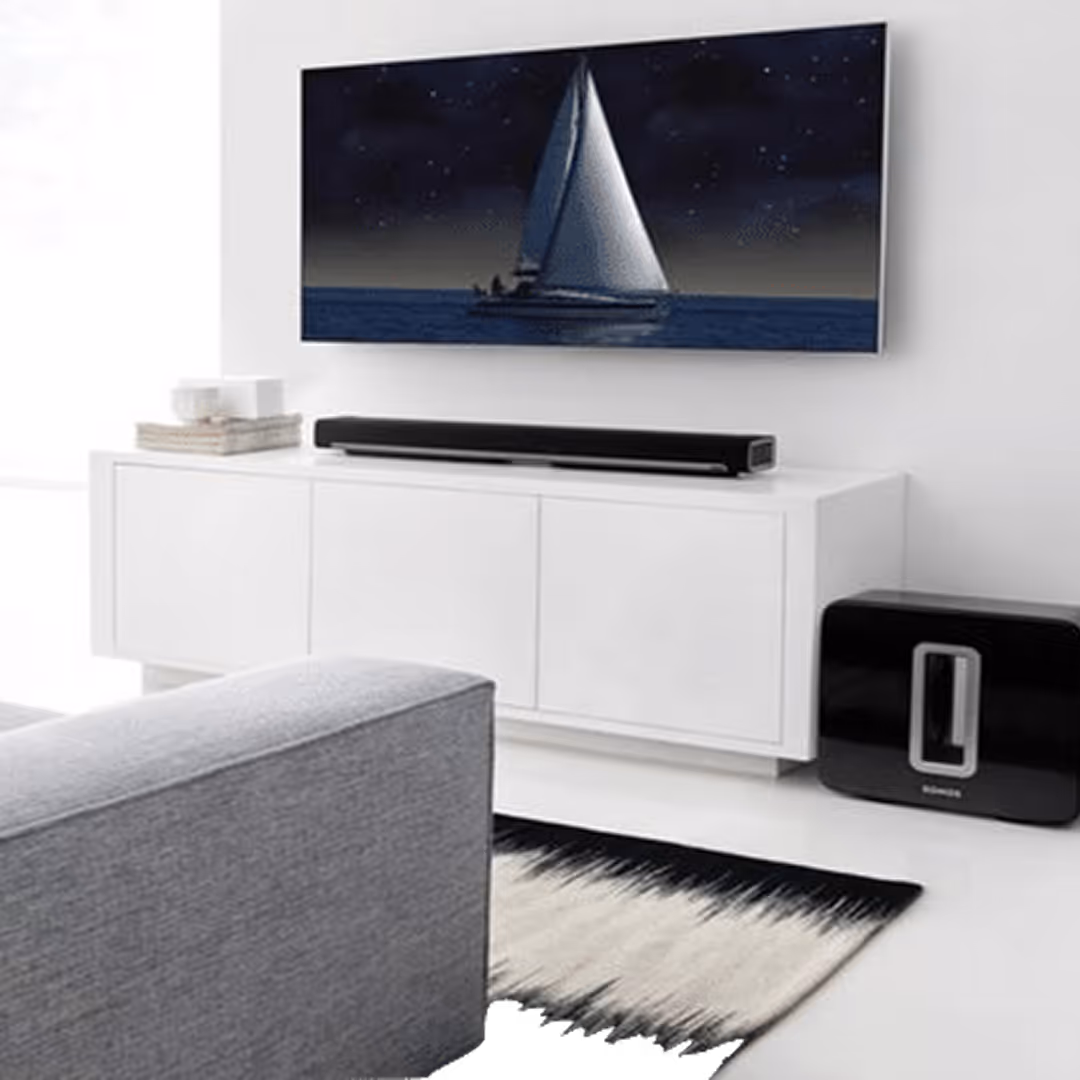 Modern home theater setup with wall-mounted flat screen TV, Sonos surround sound system, subwoofer, and minimalist white entertainment unit.