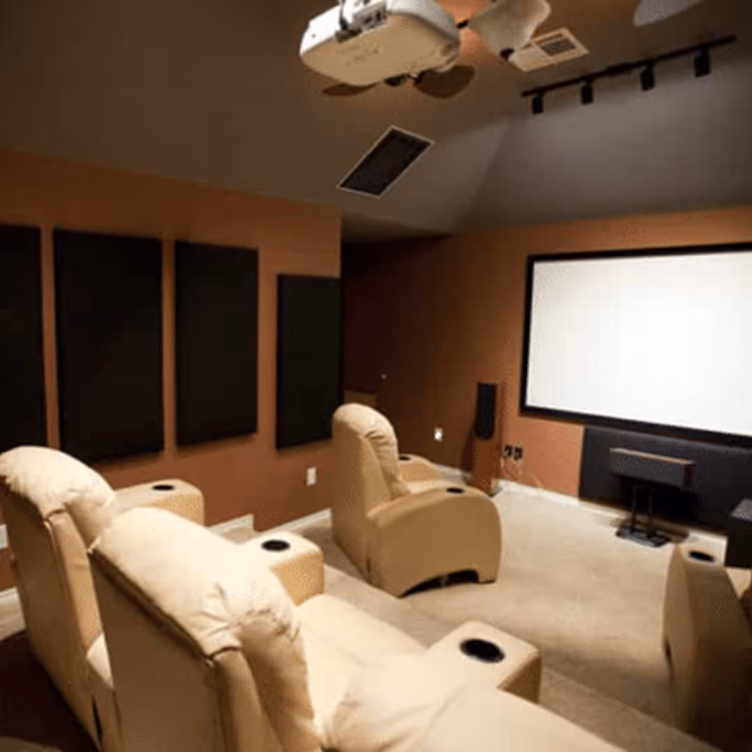 Custom-designed home theater room with large projection screen, ceiling-mounted projector, acoustic wall panels, and luxury recliner seating.