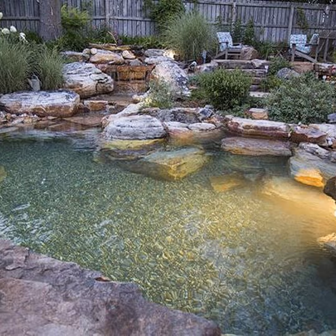 Luxury backyard pond with integrated underwater lighting and custom rock landscaping installed by Totally Wired Electric in Southern California.