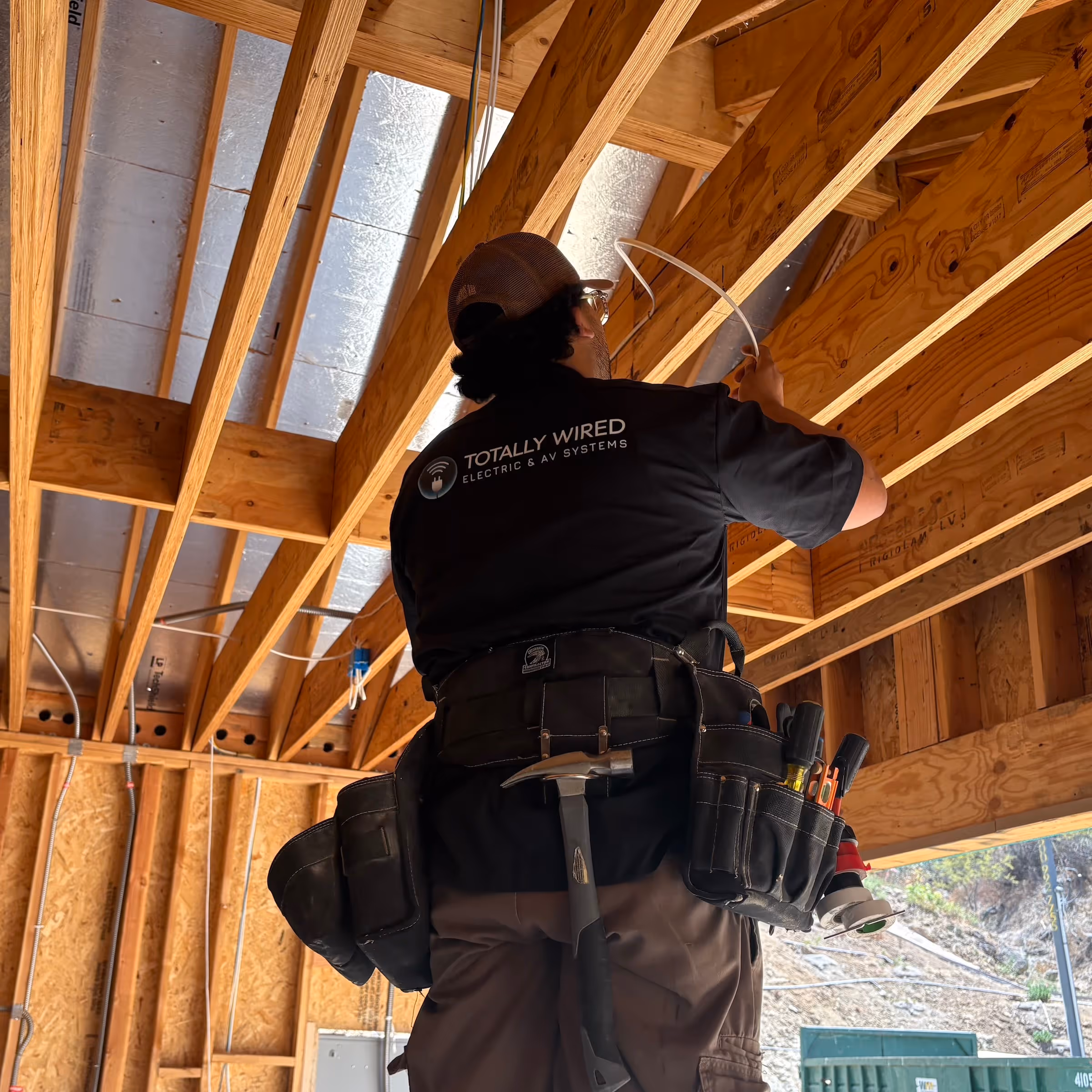 Totally Wired Electric & AV Systems technician installing electrical wiring in a custom home construction project in Southern California.
